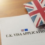 Visa application on desktop with passport and union jack wallet